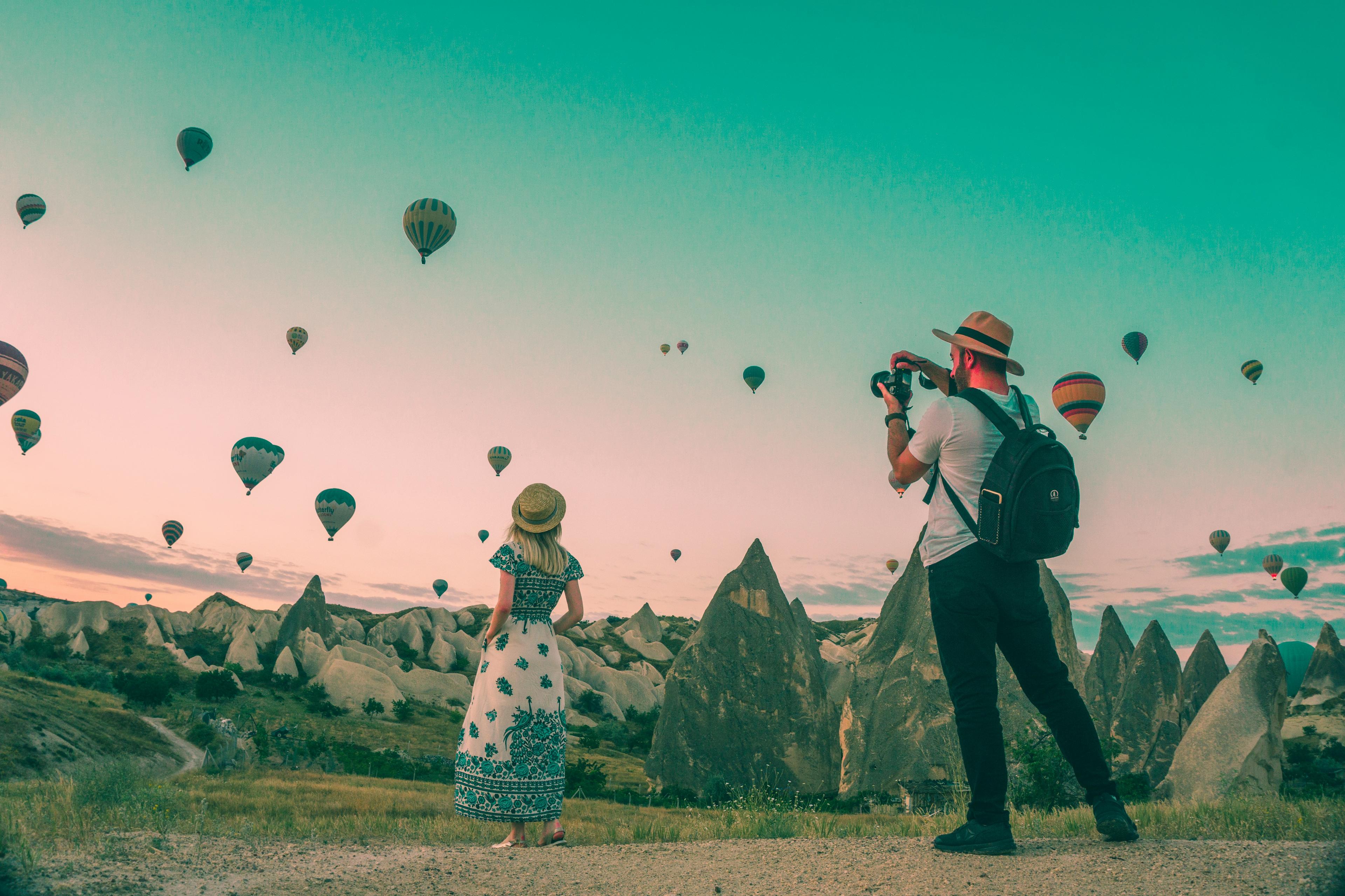 Couple travelling in cappadocia with scene of hotair balloons.